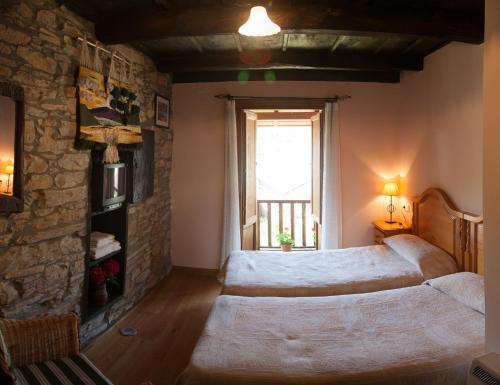 a bedroom with a large bed and a stone wall at Casa Rural Pandelo in Vega de Valcarce