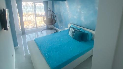 a blue room with a bed and a window at La malul marii in Mamaia Nord