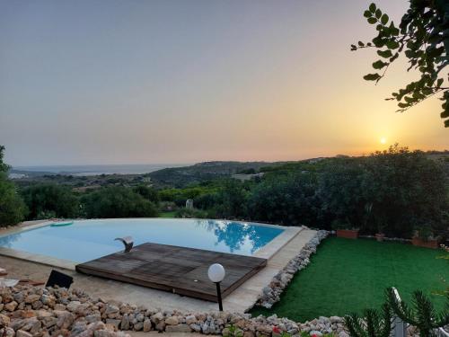 a swimming pool with a green lawn with the sunset in the background at SAN MARTIN WELLNESS RETREAT (Upper) in Il-Palma