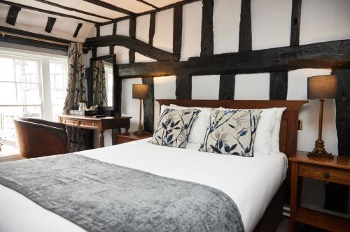 a bedroom with a large white bed and a desk at White Hart Hotel by Greene King Inns in Braintree