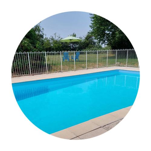 a swimming pool with a fence and an umbrella at B&B Franglaise in Romagne