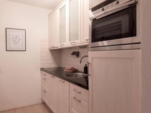 eine weiße Küche mit einer Spüle und einer Mikrowelle in der Unterkunft Vakantiehuis Hoog Noordwijk in Noordwijkerhout