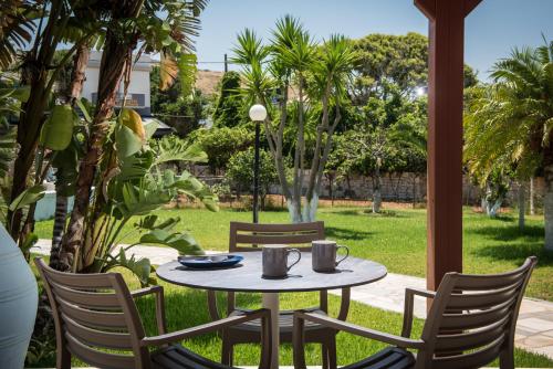een tafel en stoelen op een patio met een tuin bij Ariadni Apartments in Karteros