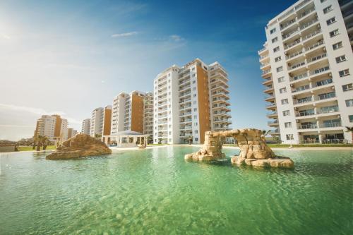 a pool of water in front of tall buildings at Amadeus Holiday Apartments in Caesar Resort & SPA, Long Beach in Perivolia tou Trikomou
