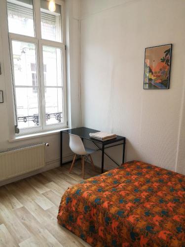 a bedroom with a bed and a desk and a window at Chambre privée centre ville in Douai