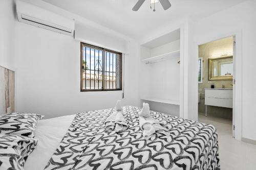 een witte slaapkamer met een zwart-wit bed bij Chalet Villasol Con Piscina in Alicante