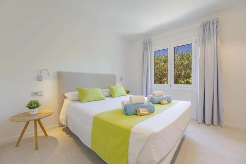 a bedroom with a large white bed with yellow and blue pillows at Cielo de Bonaire in Alcudia