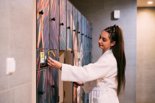 a woman in a white dress is looking at a wall at Hotel Kotarz Spa&Wellness in Brenna