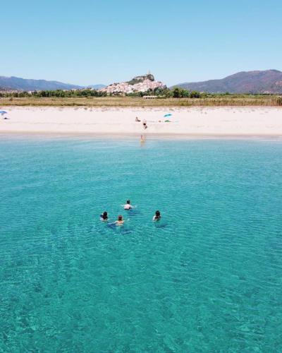 three people swimming in the water near a beach at Casa Vacanze Relaxia in Posada