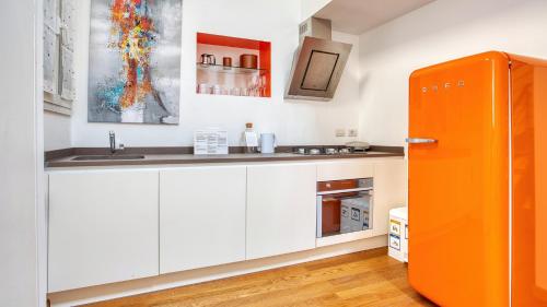 een keuken met witte kasten en een oranje koelkast bij Italianway - Paisiello 4 B in Milaan