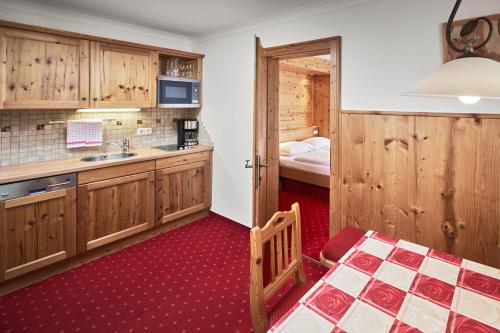 eine Küche mit Holzschränken und ein Bett in einem Zimmer in der Unterkunft Hotel Gasthof Siggen in Neukirchen am Großvenediger