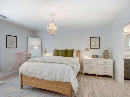 ein weißes Schlafzimmer mit einem Bett und einem Kronleuchter in der Unterkunft Crawford Carriage House in Savannah