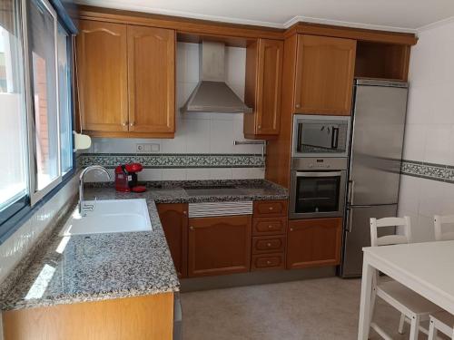 a kitchen with wooden cabinets and a sink and a refrigerator at Bonito adosado en zona muy tranquila in Benicàssim
