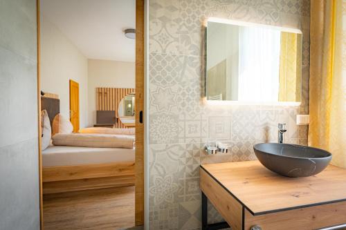 a bathroom with a bowl sink and a bedroom at Lorettohof Hotel Garni in Gaal