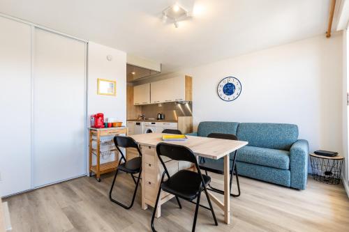a living room with a table and chairs and a couch at 2 pièces face océan, Lacanau in Lacanau