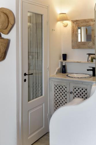 a white bathroom with a sink and a door at Ilivatos - Elegant Villa on the Caldera's Edge in Oia