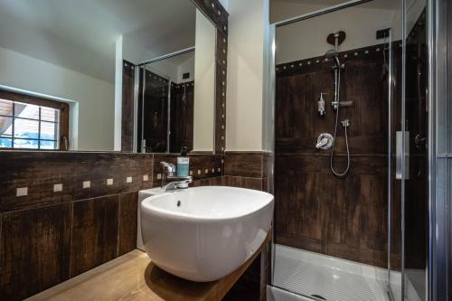 La salle de bains est pourvue d'un lavabo blanc et d'une douche. dans l'établissement Alpine Forest Hotel, à Champoluc