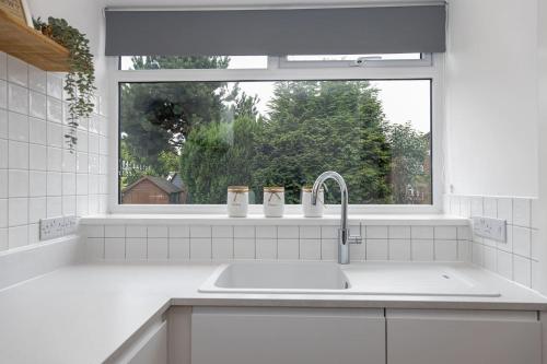 a white kitchen with a sink and a window at Scandi Inspired Home In Eccles in Manchester