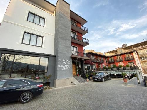 um edifício com dois carros estacionados num parque de estacionamento em Alliance Hotel em Tbilisi