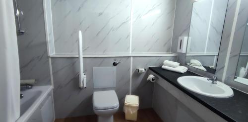 uma casa de banho branca com um lavatório e um WC em Sachas Hotel Manchester em Manchester