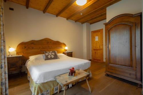 a bedroom with a large bed with a wooden headboard at Alpine Forest Hotel in Champoluc