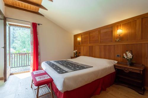 a bedroom with a bed and a desk and a window at Alpine Forest Hotel in Champoluc