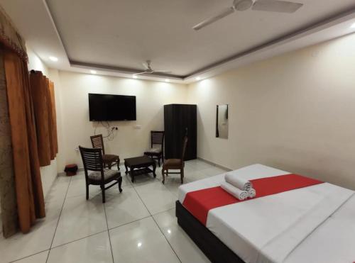 1 dormitorio con 1 cama, TV y sillas en OYO Hotel Aerotech, en Nueva Delhi