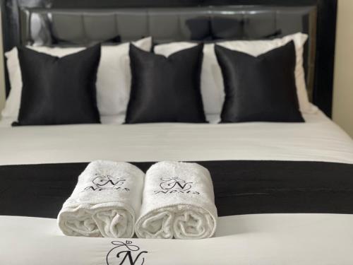 a bed with two towels on a bed with black pillows at Oak Nest in Kericho