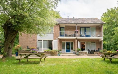 a house with two picnic tables in the yard at Appartement Zuiderstrand in Zoutelande
