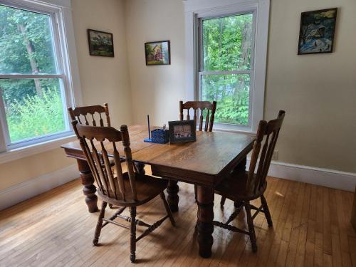 uma mesa de jantar em madeira com 4 cadeiras e 2 janelas em And.N Bed & Breakfast em Gray