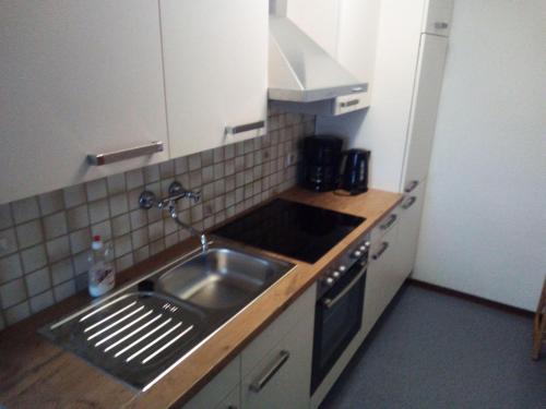 Il comprend une petite cuisine équipée d'un évier et d'une cuisinière. dans l'établissement Nordsee-Ferienanlage-Wohnung-Baltrum, à Dornumersiel