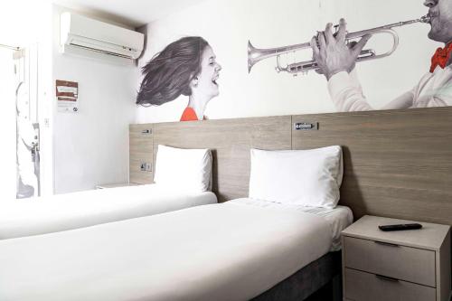 two beds in a hotel room with a picture of a trumpet at Heeton Concept Hotel - Kensington London in London