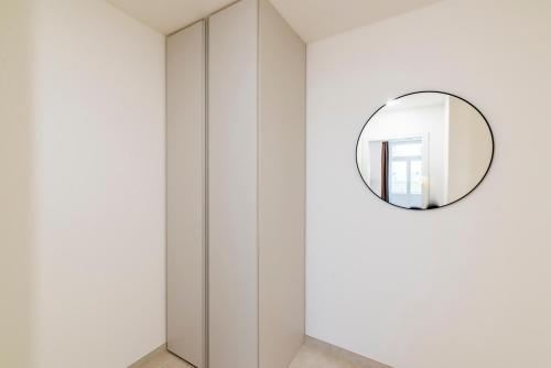 a mirror hangs on the wall of a white room at Petrin Tower Residence in Prague