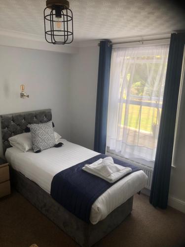 a bedroom with a bed and a window with blue curtains at The Havelock in Shanklin