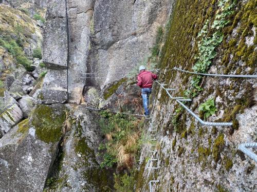 a man walking on a rope bridge on a mountain at Casa do Monte in Castro Daire