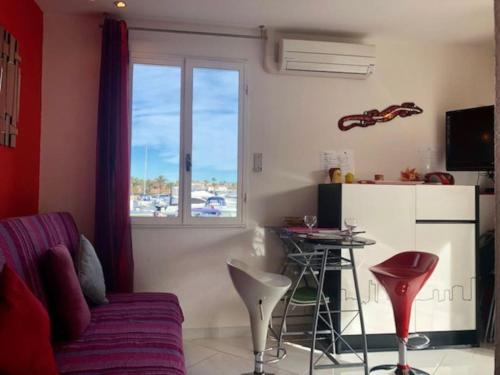un salon avec un canapé, une table et une fenêtre dans l'établissement Villa 16, Port Vénus au village naturiste, au Cap d'Agde