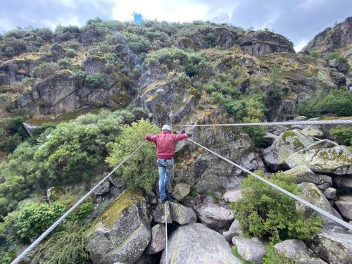 a man walking on a rope bridge over a mountain at Casa do Monte in Castro Daire