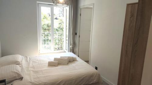 une chambre avec un lit avec des draps blancs et une fenêtre dans l'établissement Baie des anges proche mer 102, à Nice