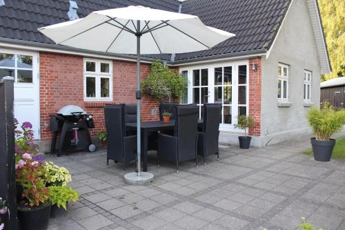 a patio with a table and an umbrella at Large modern family room - “Arnely” in Tommerup