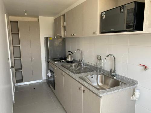 a kitchen with a sink and a microwave at Departamento con piscina. in Viña del Mar