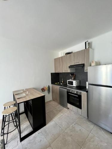 une cuisine avec une table et un réfrigérateur en acier inoxydable dans l'établissement Bel appartement avec balcon en centre-ville, à Nice