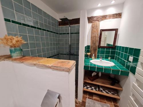 a green tiled bathroom with a sink and a mirror at DOMAINE DE LABROUSSE, Maison d'hôtes en Périgord in Agonac