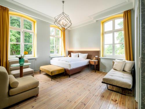 ein Schlafzimmer mit einem Bett, einem Sofa und Fenstern in der Unterkunft Stuckhotel Fettehenne in Ratingen