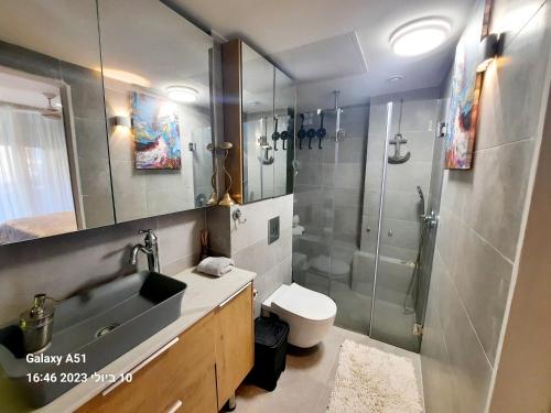 y baño con ducha, lavabo y aseo. en Sea View Suites - דירות נופש עם מקלט en Caesarea