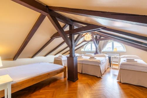 a attic room with three beds and a chandelier at Janackovo - Riverside Residence in Prague