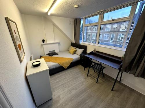 a small room with a bed and a desk at Spectacular 2 bedroom on Tower Bridge in London