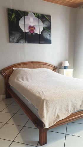 un lit dans une chambre avec une image d'une fleur dans l'établissement Les Mouflets, à Fouras