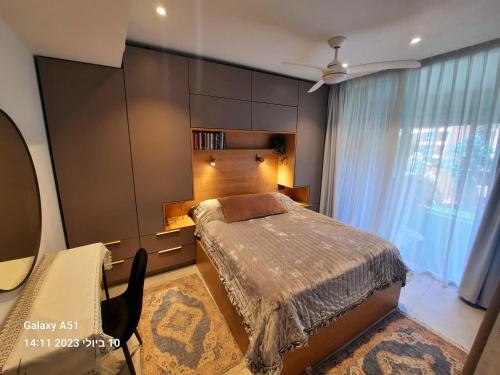 een slaapkamer met een bed en een groot raam bij Sea View Suites - דירות נופש עם מקלט in Caesarea