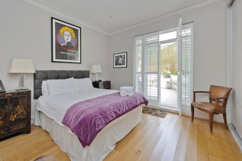 um quarto com uma cama, uma cadeira e uma janela em Beautiful Battersea Home by Clapham Junction by UnderTheDoormat em Londres