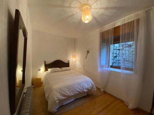 a bedroom with a white bed and a window at Casa Prada en Sanabria in Puebla de Sanabria